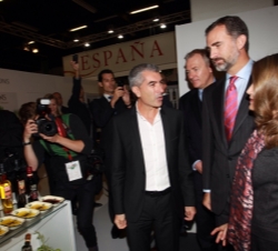 Don Felipe y Doña Letizia reciben explicaciones de uno de los expositores españoles durante su recorrido en la Feria